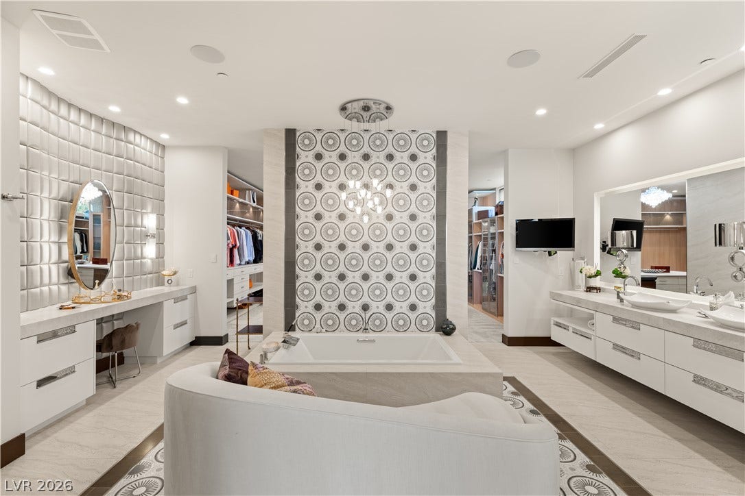 1269 Imperia Drive, Henderson, NV 89052 Geometric tile and custom vanities frame a modern soaking tub in this luxury bathroom.