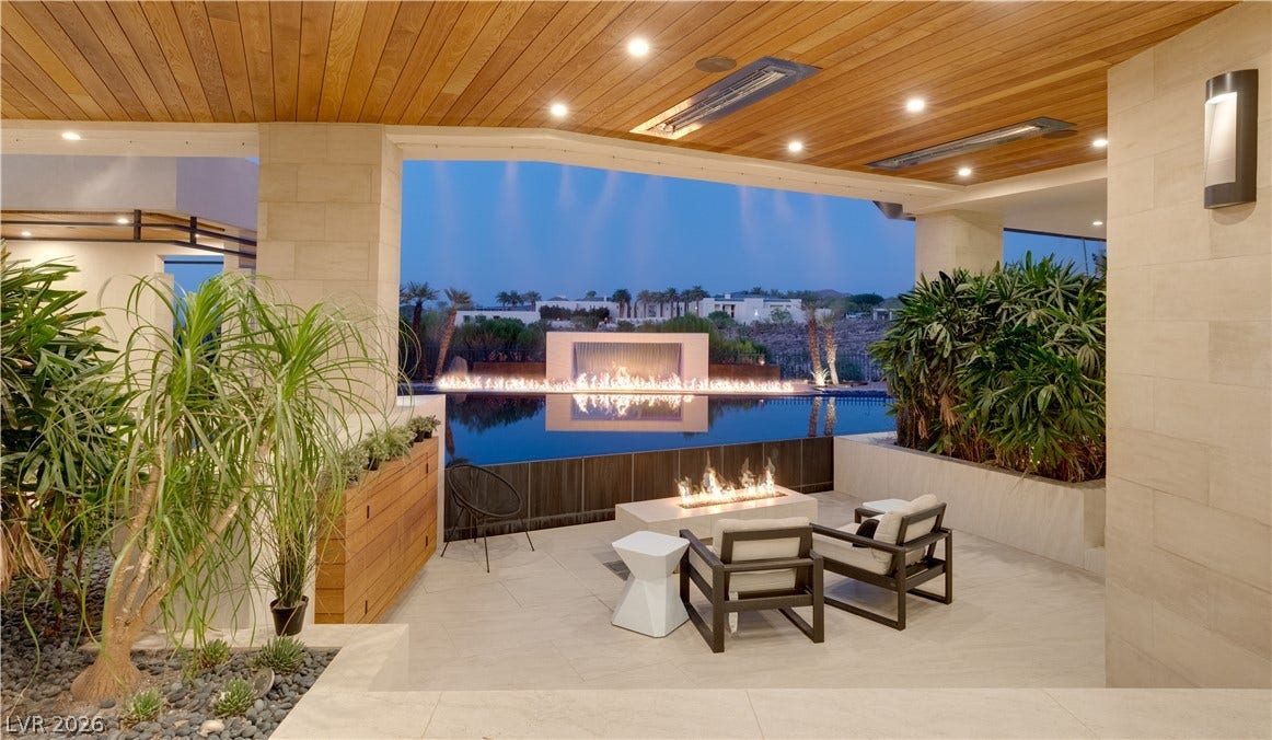 1269 Imperia Drive, Henderson, NV 89052 An covered outdoor patio looks out over a luxury swimming pool with integrated fire features.