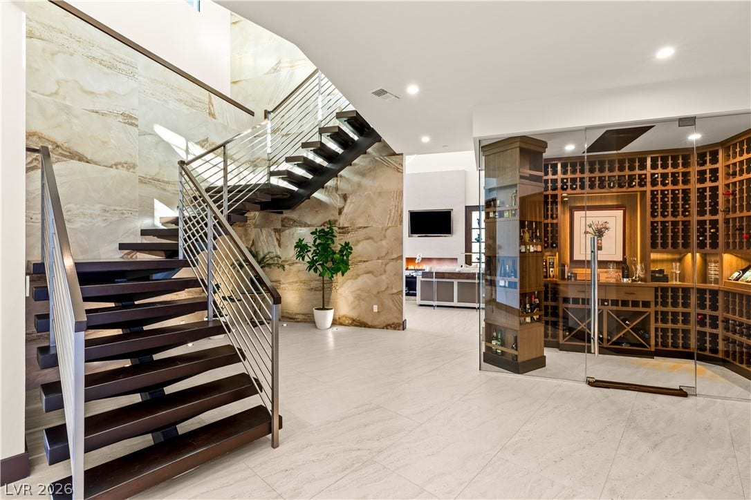 1269 Imperia Drive, Henderson, NV 89052 Sleek floating stairs and a glass-enclosed wine room elevate this grand tiled entryway.
