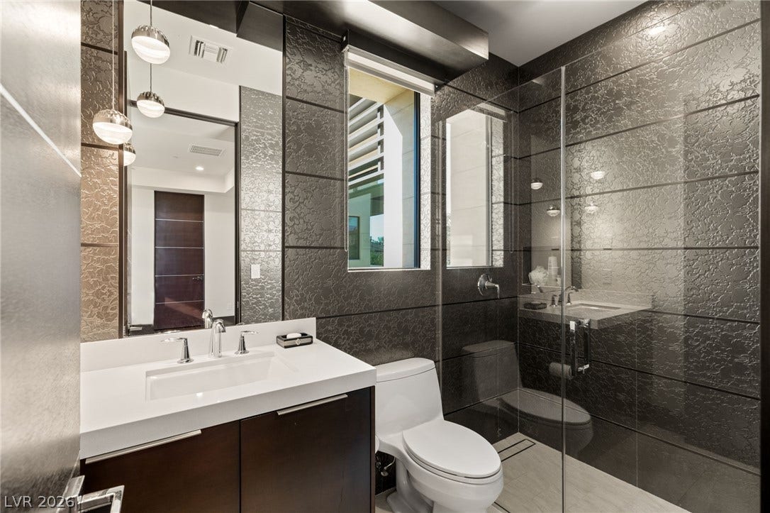1269 Imperia Drive, Henderson, NV 89052 Textured dark wall tiles and a sleek floating vanity elevate this contemporary bathroom.