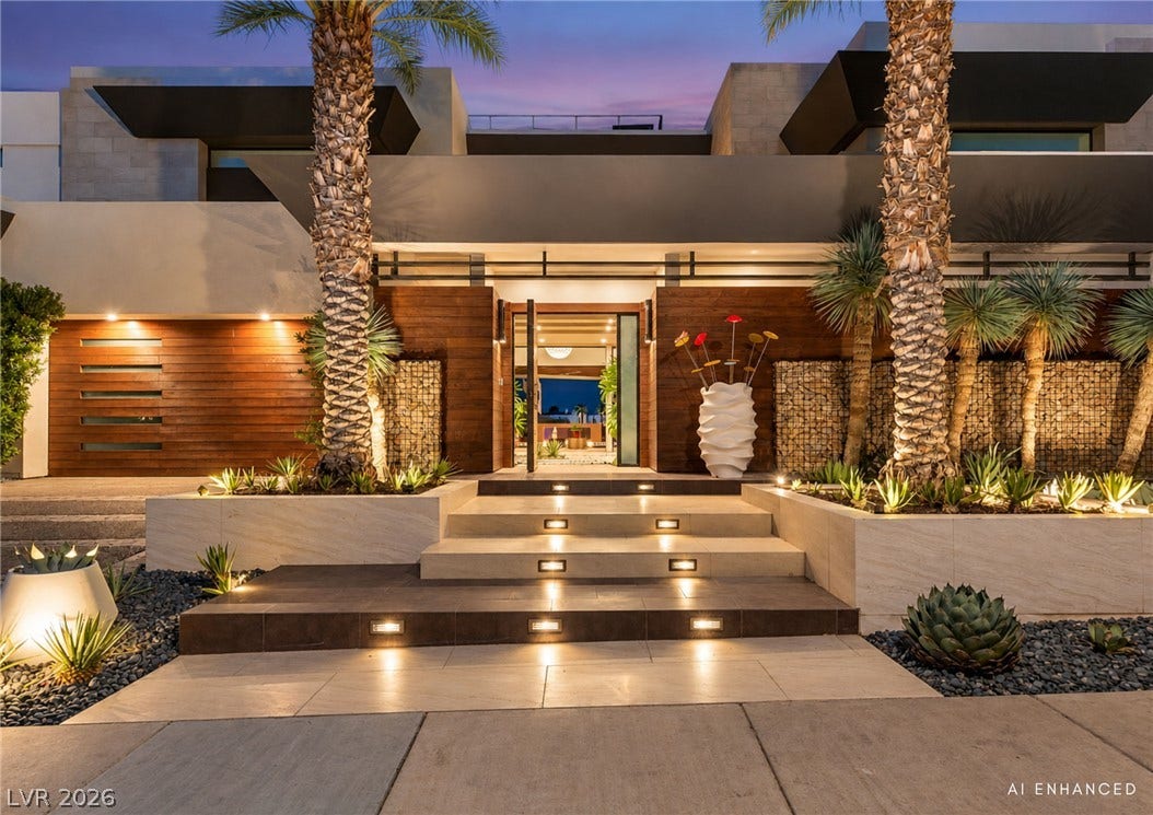 1269 Imperia Drive, Henderson, NV 89052 Illuminated stone steps lead to a grand entrance flanked by wood cladding and palm trees.