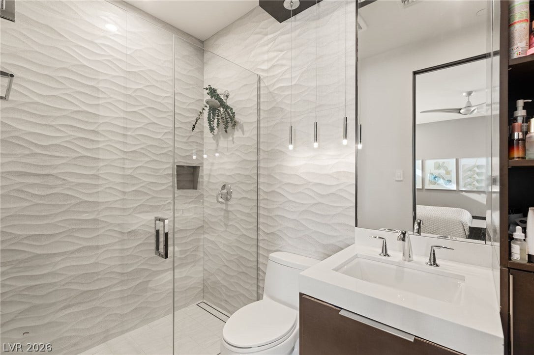 1269 Imperia Drive, Henderson, NV 89052 Textured wall tiles and a glass-enclosed shower create a modern aesthetic in this bathroom.
