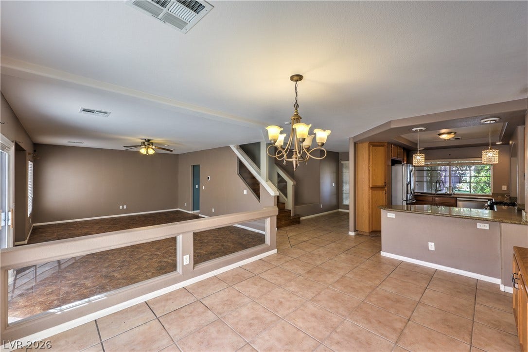 10744 Teton Village Court, Henderson, NV 89052 Gleaming tile floors stretch across a versatile open layout connecting the kitchen and living areas.