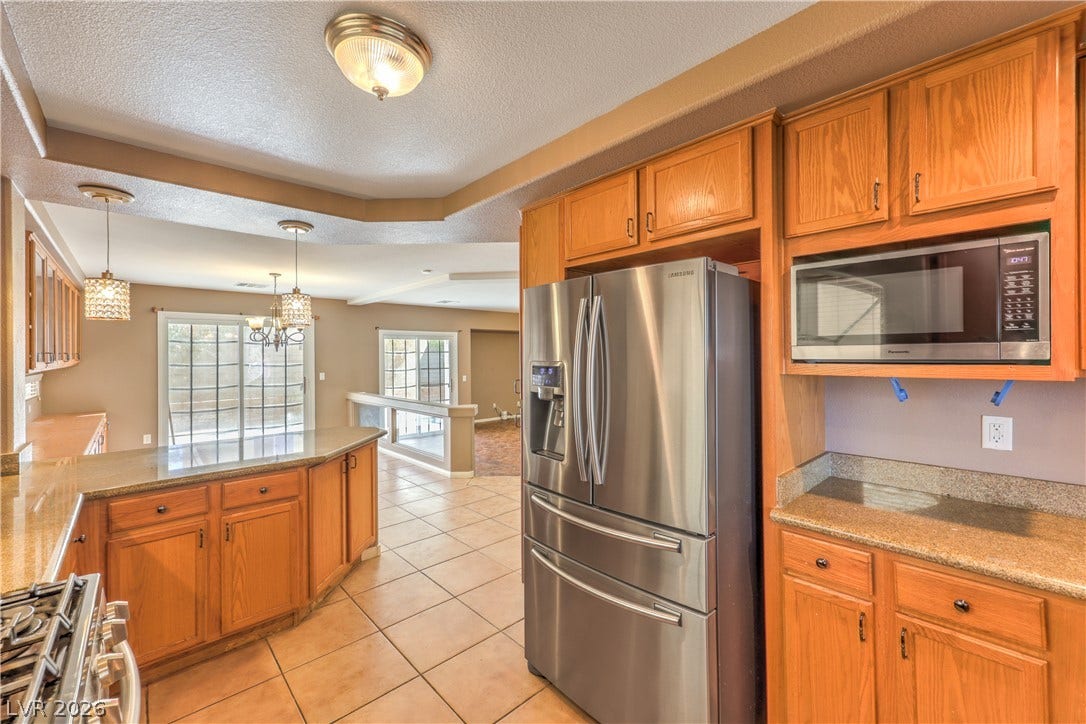 10744 Teton Village Court, Henderson, NV 89052 Gleaming stone countertops and classic wood cabinetry enrich this spacious culinary workspace.