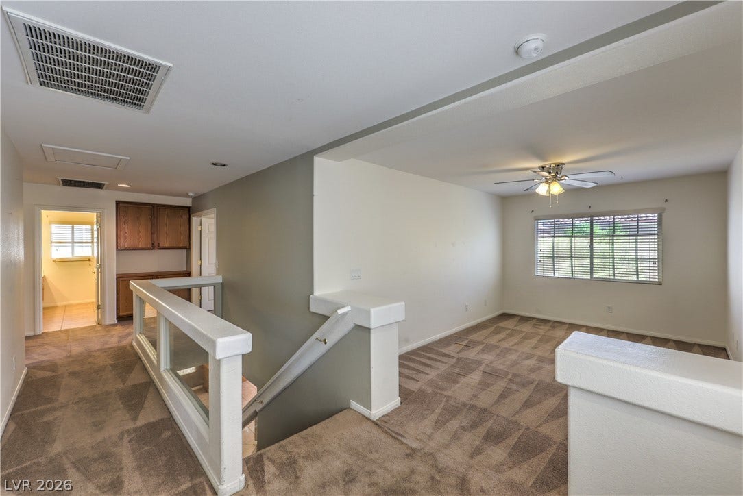 10744 Teton Village Court, Henderson, NV 89052 Plush carpeting and an open staircase define this versatile upper-level landing space.