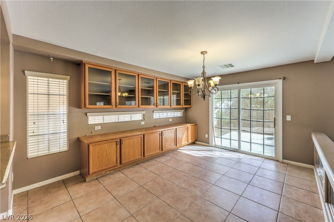 10744 Teton Village Court, Henderson, NV 89052 Tiled flooring and built-in wooden cabinetry define this casual dining space leading outdoors.