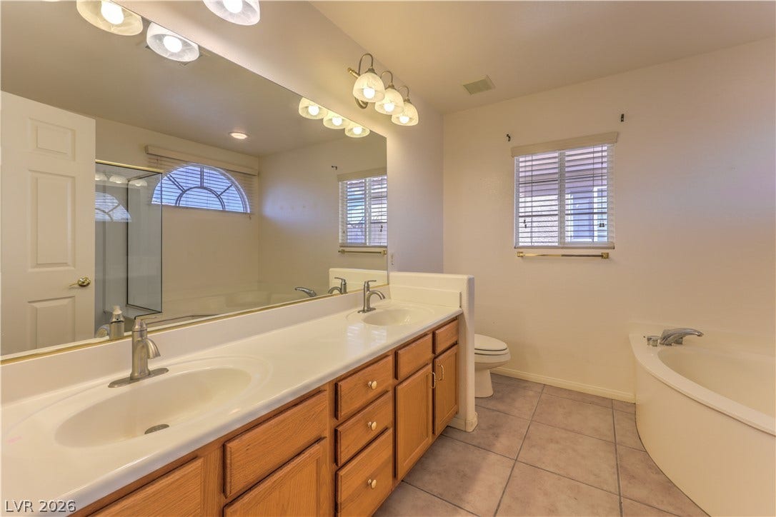 10744 Teton Village Court, Henderson, NV 89052 An expansive double vanity and a built-in soaking tub anchor this tile-floored primary bathroom.