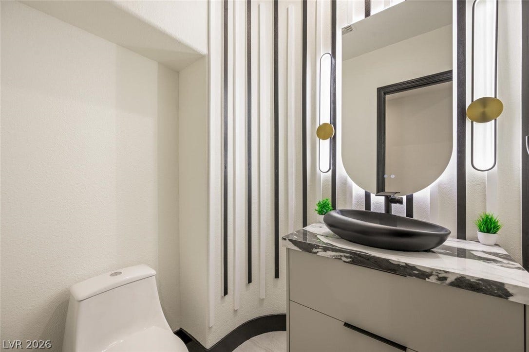 18 Wade Hampton Trail, Henderson, NV 89052 Dramatic accent wall paneling and a marble vanity bring architectural interest to this powder room.