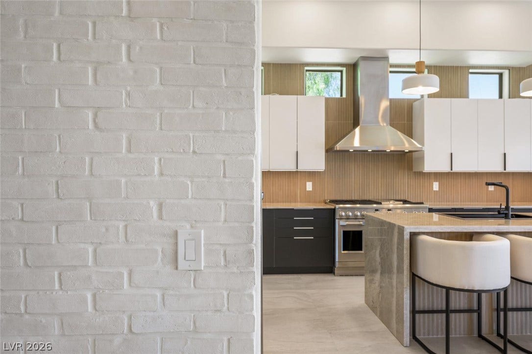 18 Wade Hampton Trail, Henderson, NV 89052 A modern kitchen presents textured walls, sleek cabinetry, and a waterfall-edge stone island.