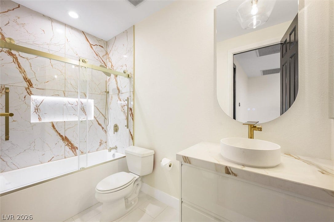 18 Wade Hampton Trail, Henderson, NV 89052 Elegant gold hardware accents complement the clean stone surfaces and marble-patterned tile tub surround.