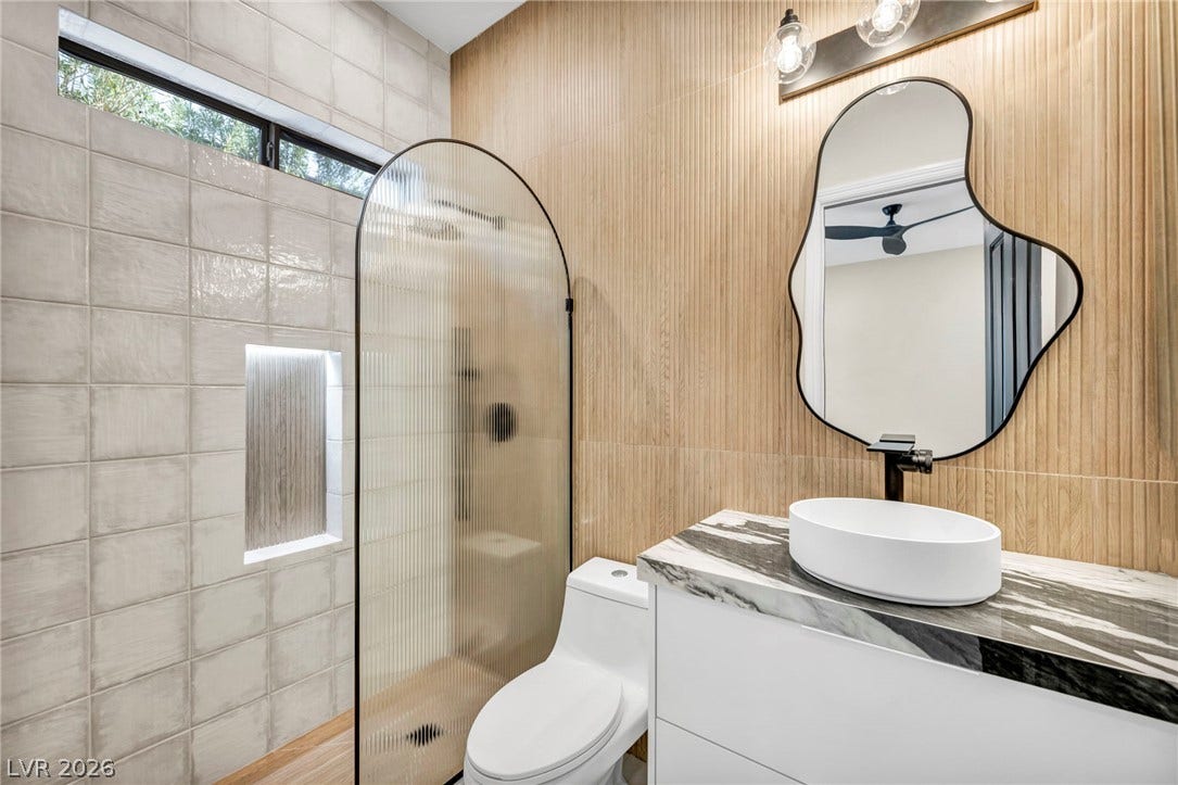 18 Wade Hampton Trail, Henderson, NV 89052 A modern marble-topped vanity and a tiled walk-in shower define this contemporary bathroom.
