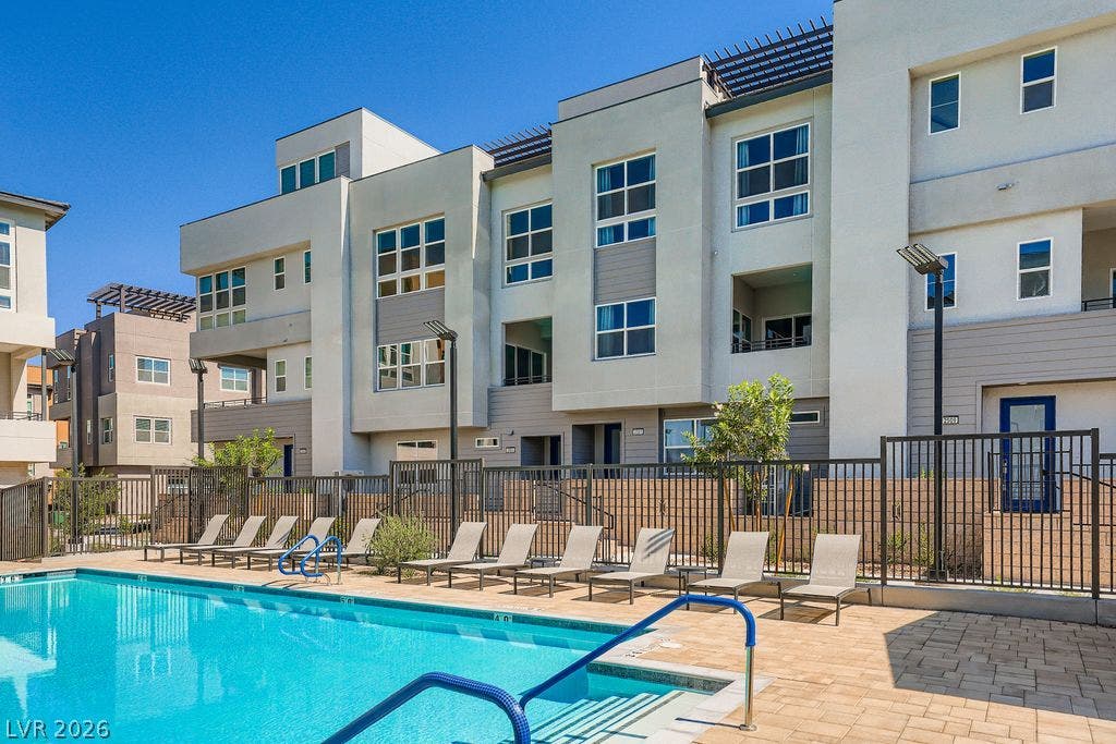 2507 Silent View Avenue, Henderson, NV 89044 A sparkling community pool sits alongside modern multi-level townhomes under clear blue skies.