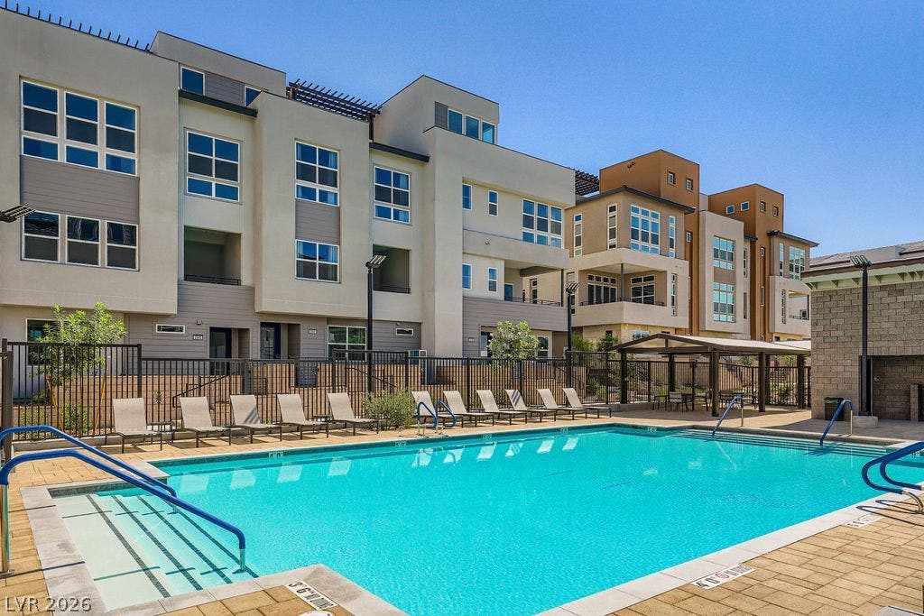 2507 Silent View Avenue, Henderson, NV 89044 Modern multi-story residential buildings frame a sparkling community swimming pool under clear blue skies.