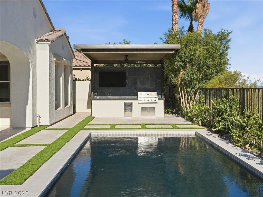 3074 Soft Horizon Way, Las Vegas, NV 89135 An inviting backyard oasis awaits with a sparkling pool and a fully equipped outdoor kitchen for seamless entertaining.