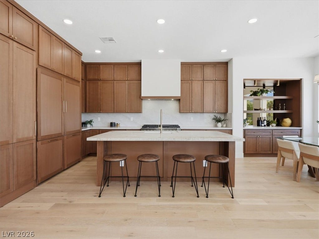 3074 Soft Horizon Way, Las Vegas, NV 89135 Blonde wood flooring anchors this open-concept kitchen with an expansive center island and custom cabinetry.