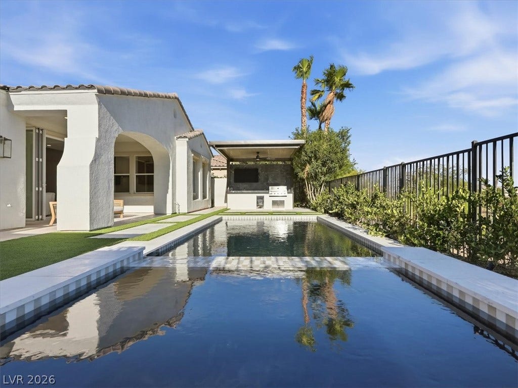 3074 Soft Horizon Way, Las Vegas, NV 89135 An inviting backyard oasis offers a sparkling pool and an integrated outdoor kitchen under a clear sky.