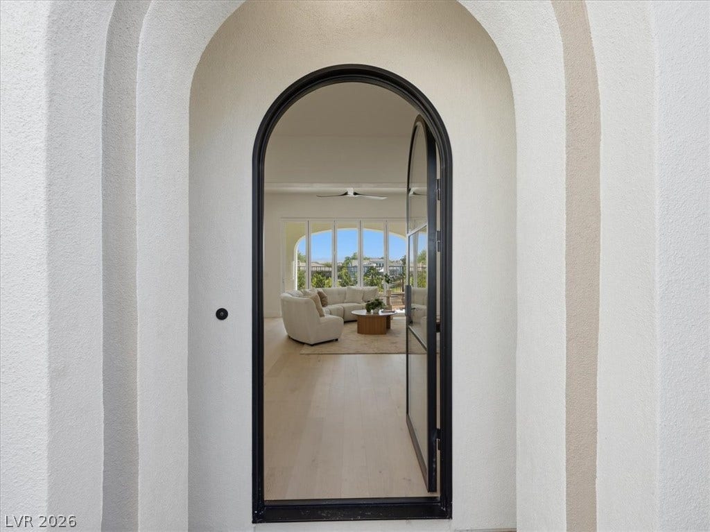 3074 Soft Horizon Way, Las Vegas, NV 89135 Arched entry with a modern glass door opens to a bright living space with hardwood flooring and ample natural light.