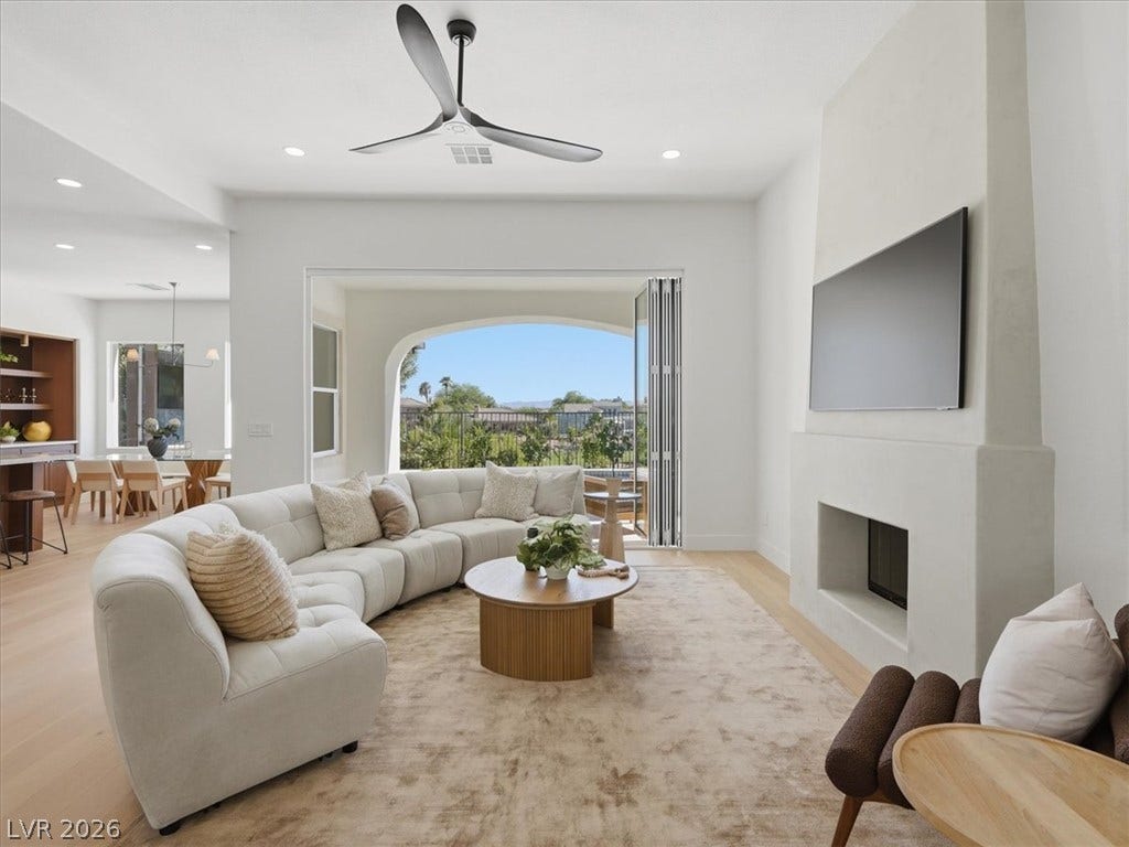 3074 Soft Horizon Way, Las Vegas, NV 89135 An inviting open-concept living area with a fireplace and wood flooring extends to an outdoor balcony.