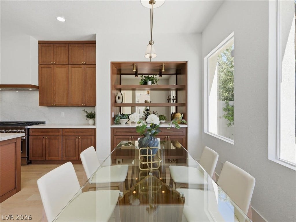 3074 Soft Horizon Way, Las Vegas, NV 89135 Natural light floods this inviting dining area, seamlessly connecting to a modern kitchen with rich wood cabinetry.