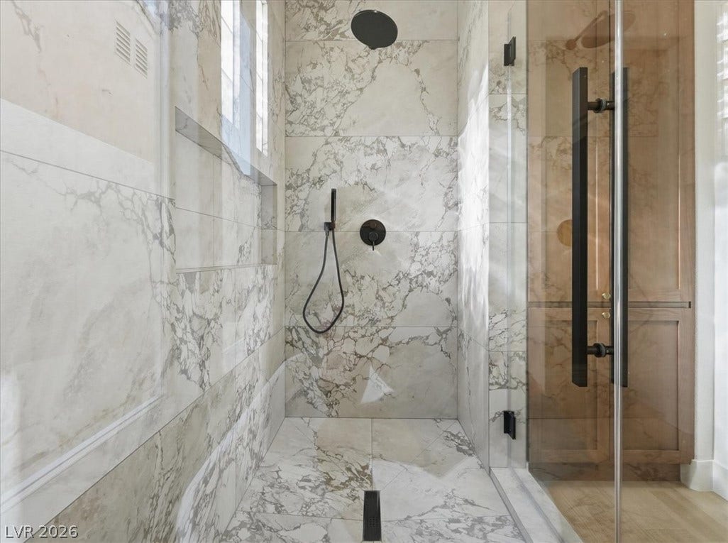 3074 Soft Horizon Way, Las Vegas, NV 89135 A well-appointed shower stall features luxurious marble-patterned tile, matte black fixtures, and a clear glass enclosure.