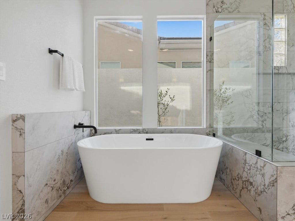 3074 Soft Horizon Way, Las Vegas, NV 89135 A spacious, naturally illuminated bathroom featuring a modern soaking tub and a sleek glass-enclosed shower.