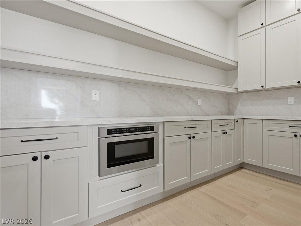 3074 Soft Horizon Way, Las Vegas, NV 89135 A sleek, contemporary kitchen boasts ample white cabinetry and light wood flooring.