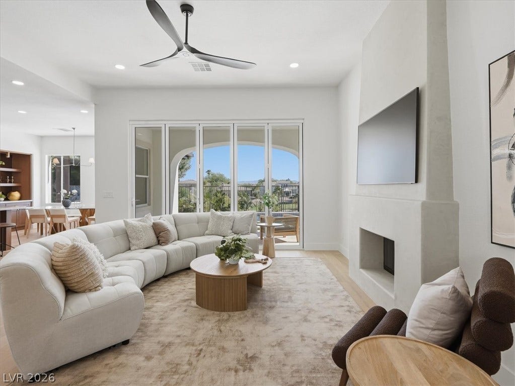 3074 Soft Horizon Way, Las Vegas, NV 89135 An inviting great room with wood flooring extends to an outdoor balcony, offering scenic views.