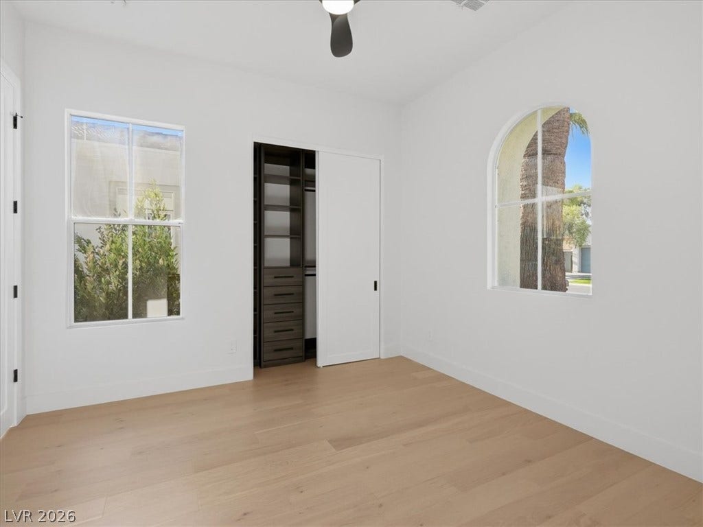 3074 Soft Horizon Way, Las Vegas, NV 89135 A quiet bedroom showcases light wood flooring and well-lit windows, one elegantly arched.