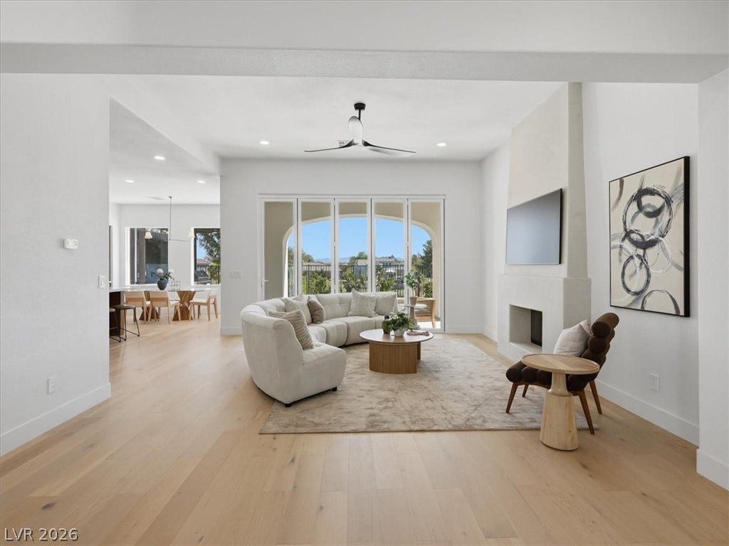 3074 Soft Horizon Way, Las Vegas, NV 89135 A graceful fireplace anchors this airy living room with warm wood flooring and outdoor access.