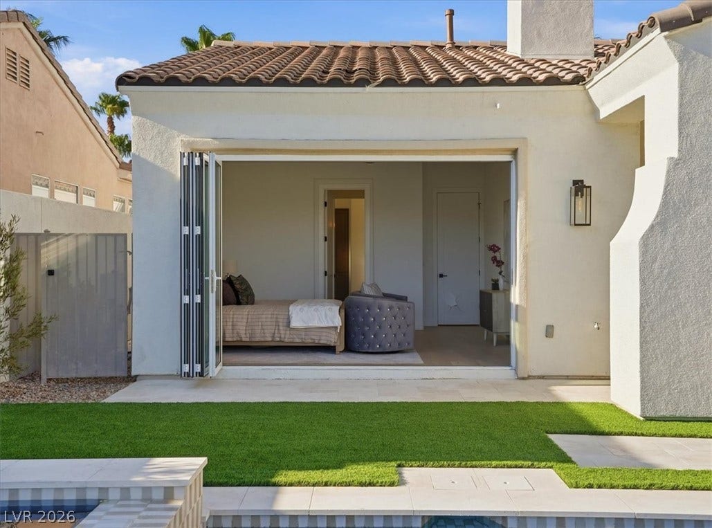 3074 Soft Horizon Way, Las Vegas, NV 89135 An inviting secondary bedroom with accordion glass doors opens to a pristine backyard with lush green turf and a sparkling pool.
