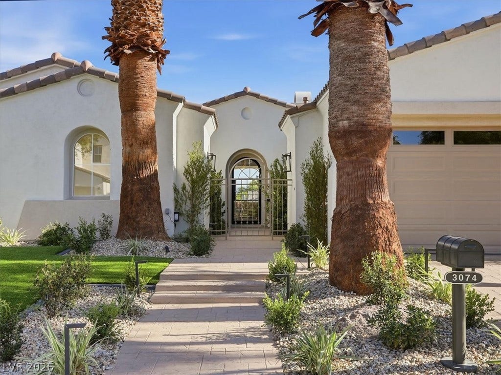 3074 Soft Horizon Way, Las Vegas, NV 89135 A well-manicured yard with palm trees and a paved walkway leads to the welcoming arched entry of this graceful stucco residence.
