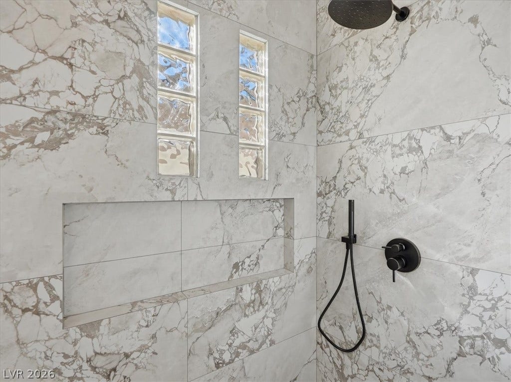 3074 Soft Horizon Way, Las Vegas, NV 89135 Marble-clad shower with integrated niche and modern black fixtures.