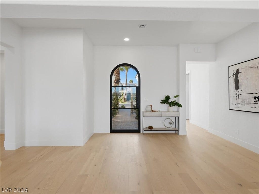 3074 Soft Horizon Way, Las Vegas, NV 89135 An arched doorway invites natural light into a luminous entry with rich hardwood flooring.