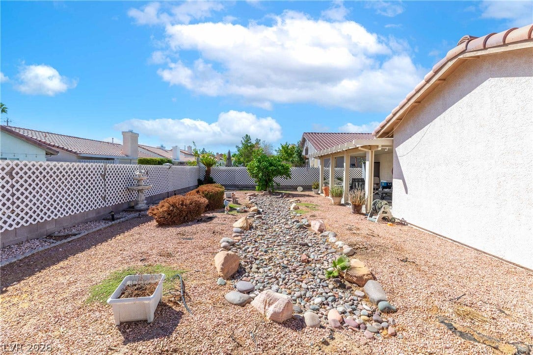 4633 Sophia Way, North Las Vegas, NV 89032 A low-maintenance desert landscape features a dry riverbed adjacent to a covered patio structure.