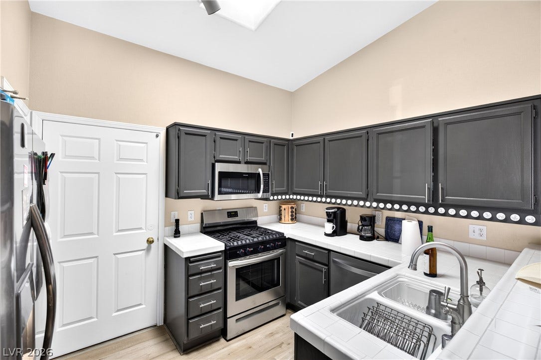 4633 Sophia Way, North Las Vegas, NV 89032 Crisp tile countertops and dark cabinetry define this functional culinary space with vaulted ceilings.