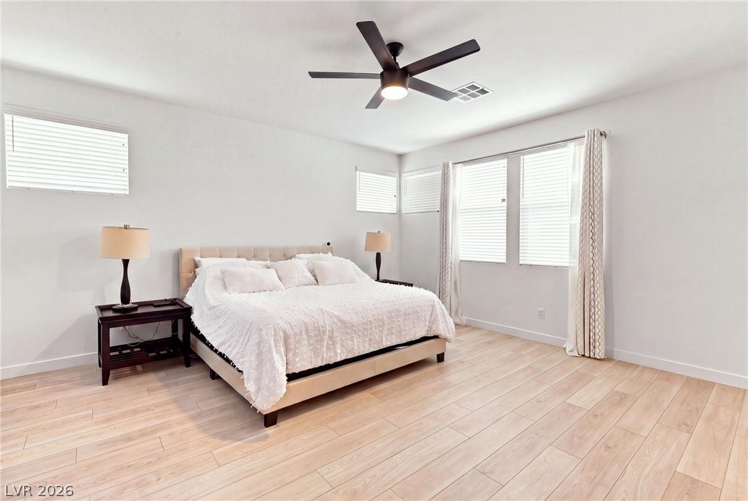 709 Emerson Creek Court, North Las Vegas, NV 89084 A well-lit bedroom features hardwood flooring and a functional ceiling fan.