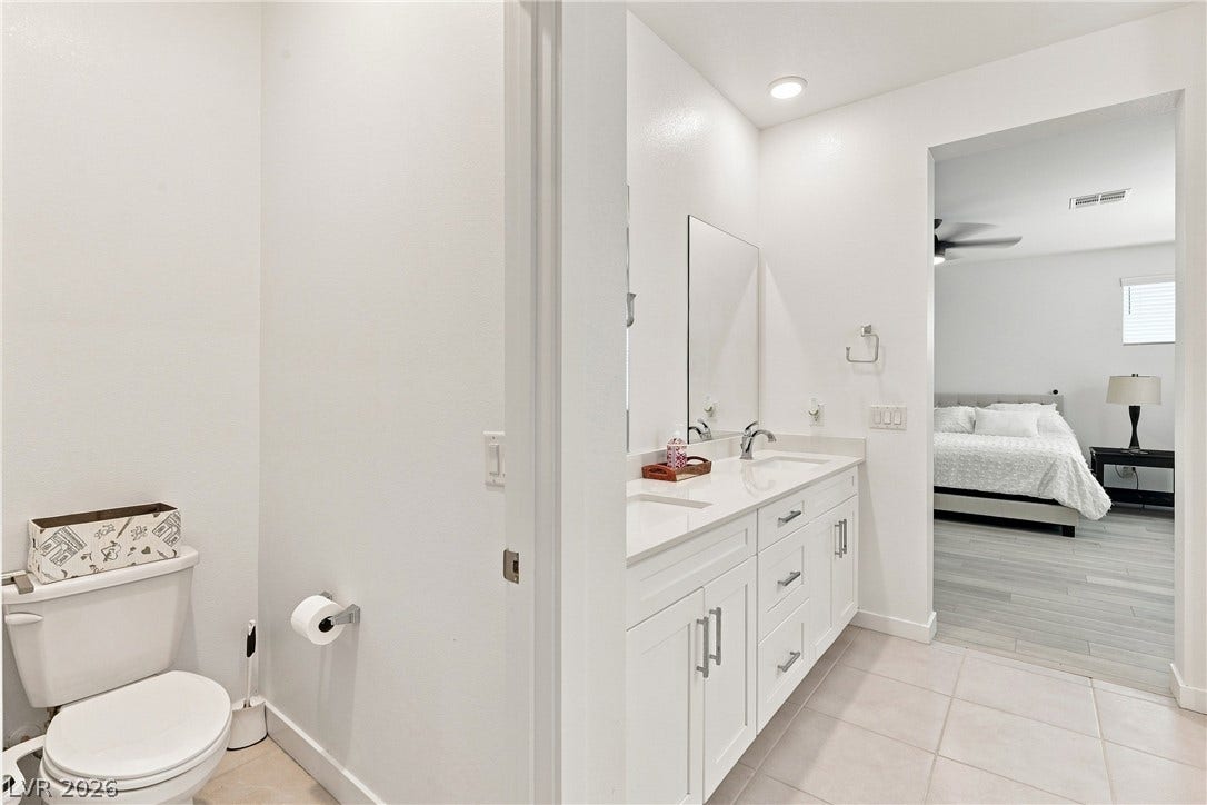 709 Emerson Creek Court, North Las Vegas, NV 89084 A pristine bathroom vanity, complete with a dual-sink setup and gleaming countertops, connects seamlessly to an adjoining bedroom.