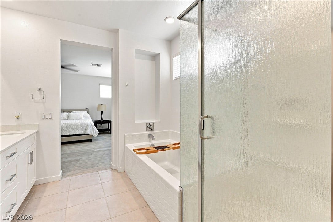 709 Emerson Creek Court, North Las Vegas, NV 89084 A well-appointed bathroom offers a separate soaking tub and shower, with a view into the primary bedroom.