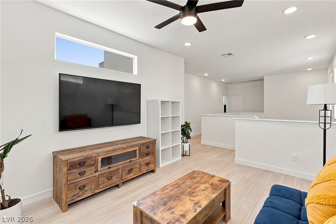709 Emerson Creek Court, North Las Vegas, NV 89084 The open-concept living space features light wood flooring, recessed lighting, and a modern ceiling fan, creating an inviting atmosphere.