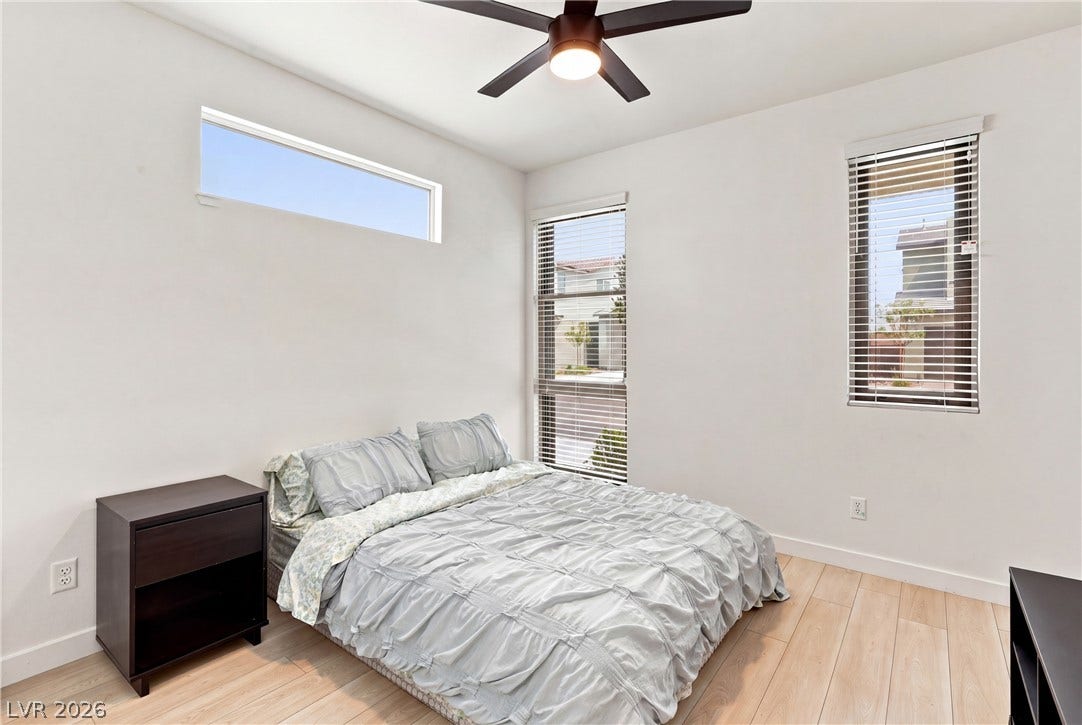 709 Emerson Creek Court, North Las Vegas, NV 89084 A well-lit bedroom features hardwood floors and multiple windows, providing a peaceful retreat.