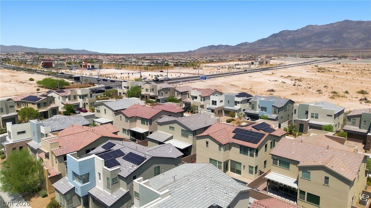 709 Emerson Creek Court, North Las Vegas, NV 89084 An aerial perspective showcases a vibrant desert community with numerous modern homes featuring diverse rooflines and solar panels.