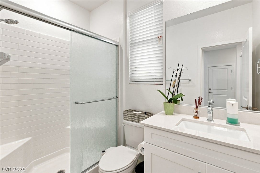 709 Emerson Creek Court, North Las Vegas, NV 89084 A well-appointed bath boasts a sleek shower with subway tile, complemented by a pristine vanity and ample mirror space.