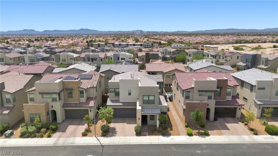 709 Emerson Creek Court, North Las Vegas, NV 89084 An aerial perspective reveals a vibrant neighborhood of modern homes nestled against a sweeping desert landscape.