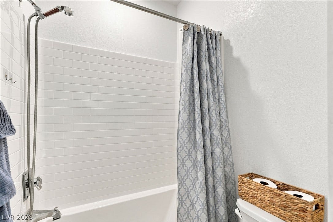 709 Emerson Creek Court, North Las Vegas, NV 89084 White subway tile surrounds a well-appointed shower-over-tub combination in this pristine bathroom.