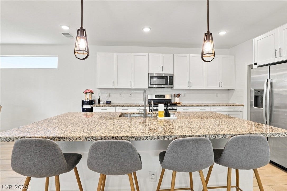 709 Emerson Creek Court, North Las Vegas, NV 89084 A well-lit kitchen presents a spacious granite island with seating and sleek stainless steel appliances.