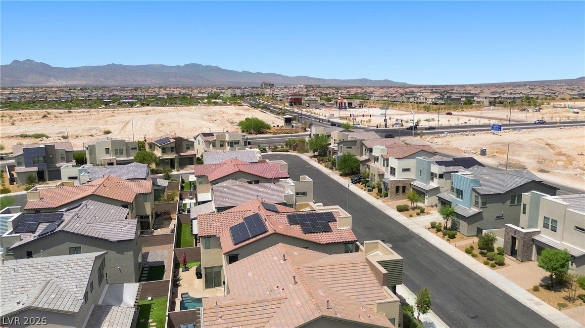 709 Emerson Creek Court, North Las Vegas, NV 89084 An aerial perspective reveals a vibrant community nestled against distant mountains, showcasing modern homes with varied rooflines.
