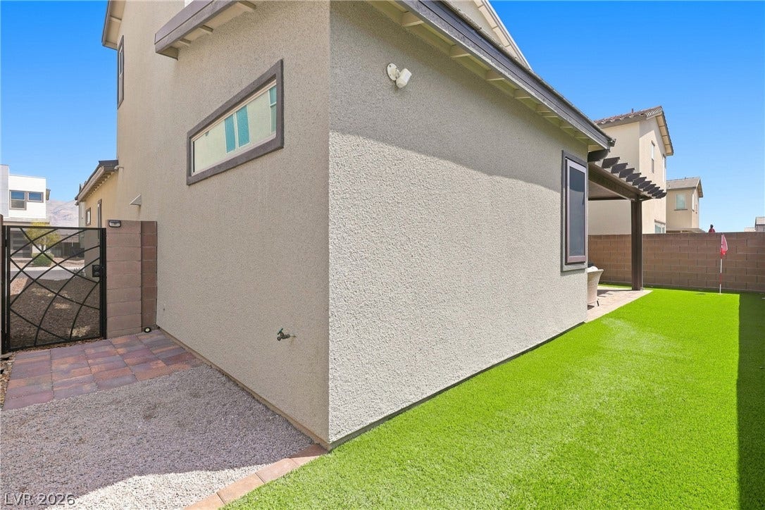 709 Emerson Creek Court, North Las Vegas, NV 89084 A low-maintenance yard features artificial turf and a private gated entry, complementing the modern stucco exterior.