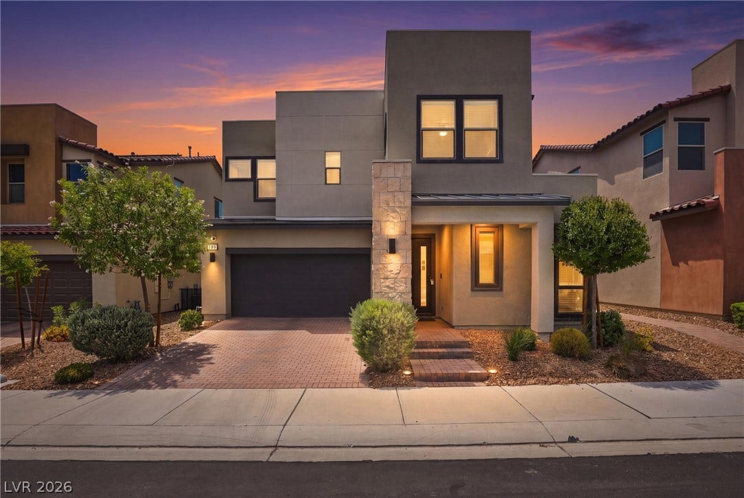 709 Emerson Creek Court, North Las Vegas, NV 89084 Modern facade illuminated by dusk's glow, featuring a paver driveway leading to an integrated garage.