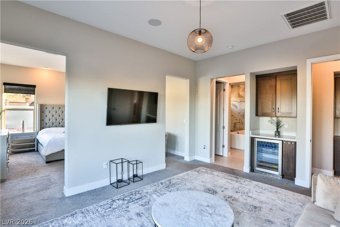 7851 W Wigwam Avenue, Las Vegas, NV 89113 Living room featuring light carpet, beverage cooler, and a bar