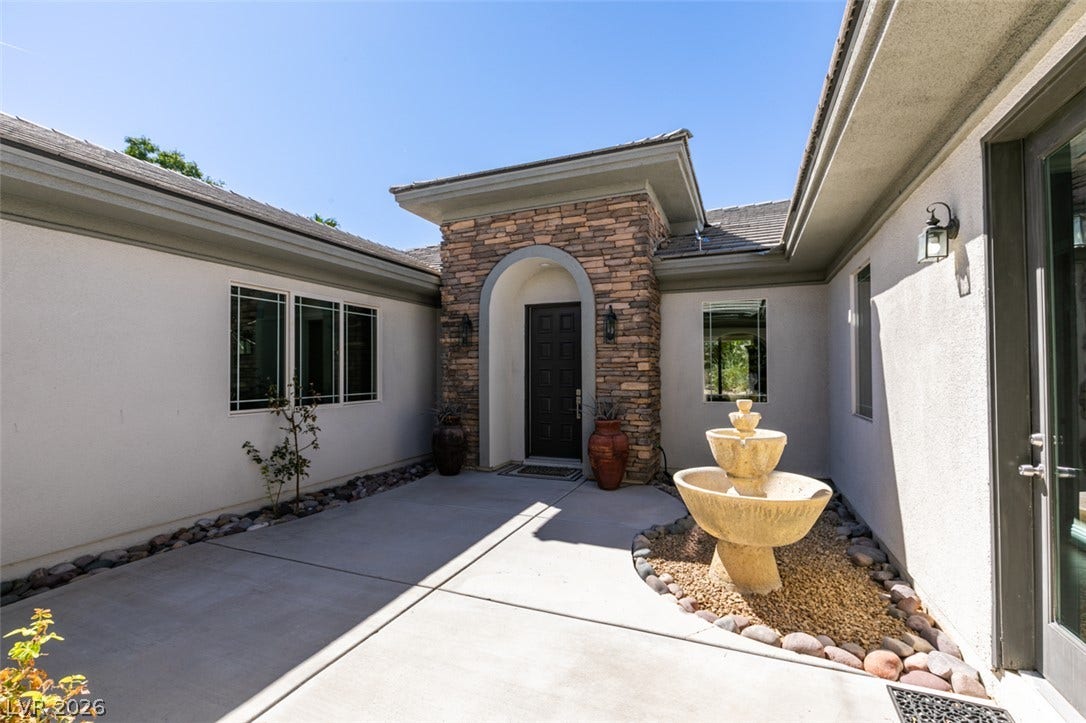 An inviting stone-accented entryway welcomes guests with a classic tier fountain.